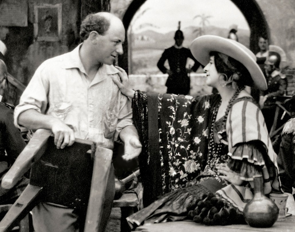 A rare behind-the-scenes shot from the film Carmen (1915) by Cecil B. DeMille, showing actress Geraldine Farrar, who played Carmen, talking to the director