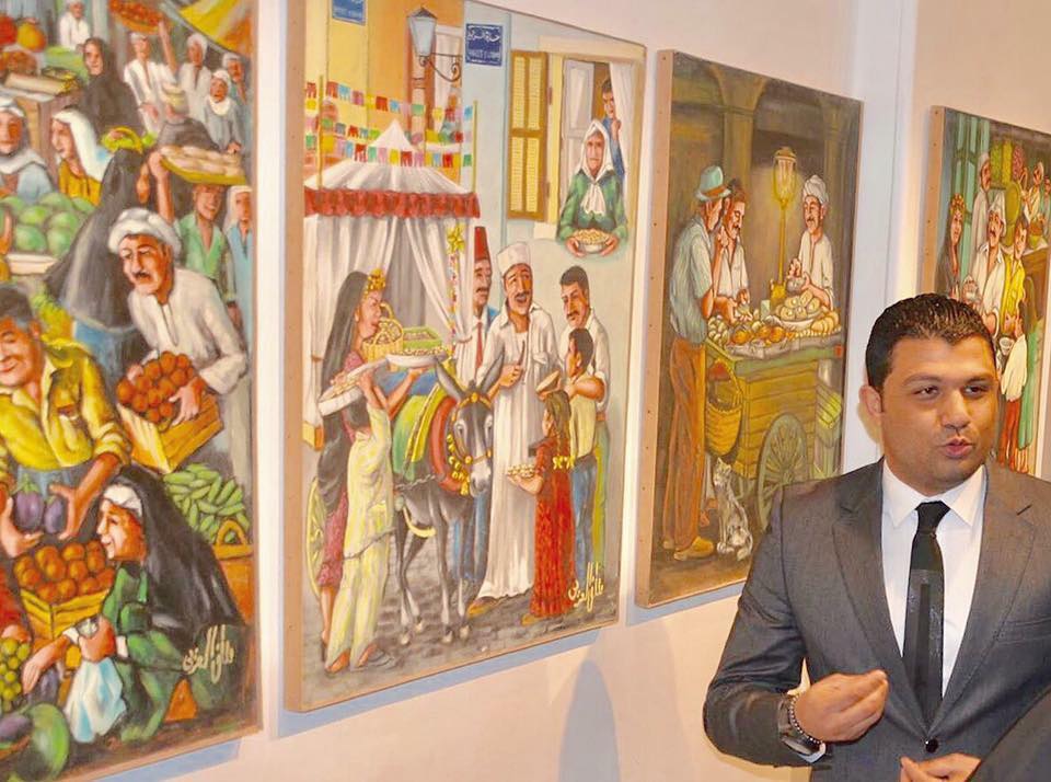 محسن العزبي أمام لوحات والده الفنان مصطفي العزبي خلال معرض استيعادي عام 2025
