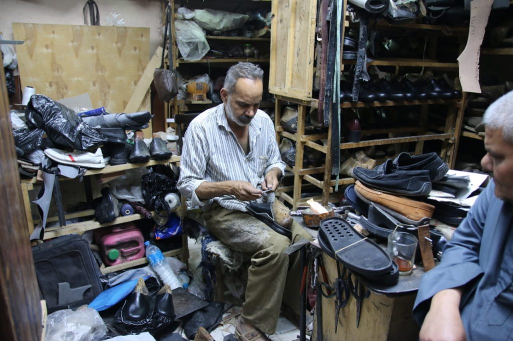 Hany, a master cobbler, meticulously repairs footwear within the vibrant arteries of Luxor’s Market Street. Photo: Abul-Hassan Abdulsattar